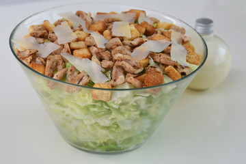 Classic Chicken Caesar Salad in a clear glass bowl with crisp lettuce, tender grilled chicken pieces, croutons, and Parmesan cheese side view of healthy fresh salad