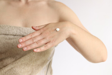 Hand cream. Close-up of young woman's hand with moisturizing cream. Skin care. Woman in towel applying cream to skin of hands. Healthy skin. Cosmetology. Daily routine