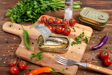An open can of sardines on cutting wooden board