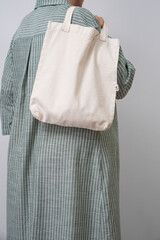 Anonymous woman holding a beige reusable shopping bag. Shopper