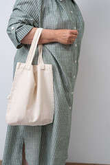 Anonymous woman holding a beige reusable shopping bag. Shopper