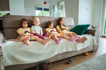 Four children relax on a couch in colorful attire
