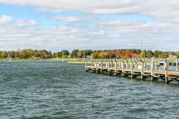 Empty wooden piers in a harbour on a partly cloudy autumn day. Anchored boats are visible in background.
