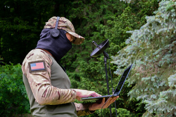 A soldier wearing a balaclava and headphones captures acoustic signals in the field.