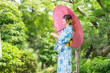 新緑の公園を歩く着物姿の若い女性