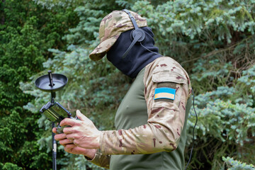 Fototapeta premium A Ukrainian drone operator wearing a mask and headphones works in forest conditions.