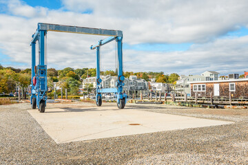 Boat lift crane on a dock on a river marina on a sunny autumn day. Autumn colours are in background.