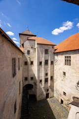 Fototapeta premium Svihov water castle courtyard with tower and orange roof on sunny summer day in Czechia