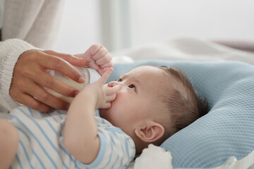 A loving mother gently holds her sleeping newborn baby on a cozy bed, capturing a tender moment of bonding and warmth