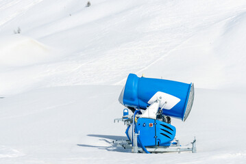 Close up a snow cannon along a ski run in the Swiss Alps on a sunny early spring day