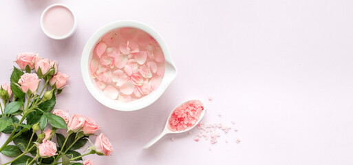 Spa and beauty routine concept with pink roses and essence water with petals