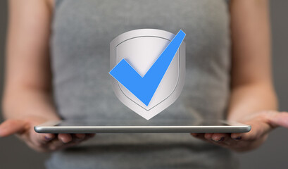Image of a person holding a tablet with a digital shield and checkmark, representing data security...