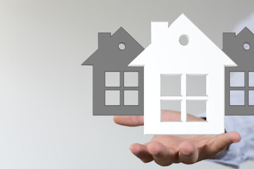 Image of a hand holding 3D house models, ideal for real estate, property, and home concepts.