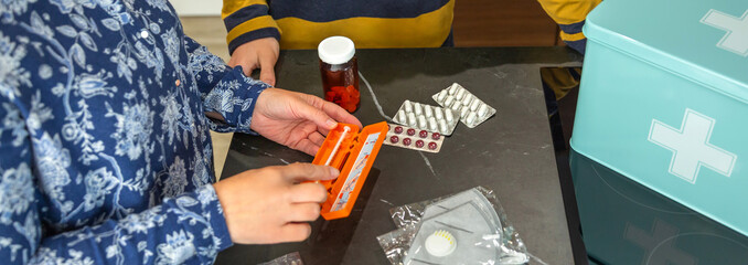 Unrecognizable mother showing how to use medical injection with pre filled syringe to son while organizing first aid emergency kit, providing healthcare guidance and education. 72 hour survival kit.