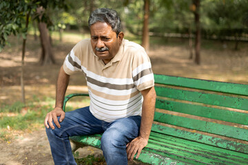 Indian senior man having knee pain at park. 
Pain In The Elderly, Health care