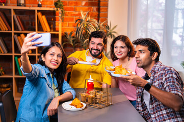 College friends click selfie while bonding over samosas and chai at casual indoor cafe setting