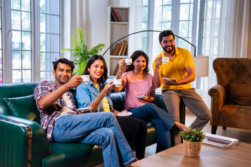 Happy Indian youth sipping chai and bonding on sofa in a cozy indoor home environment