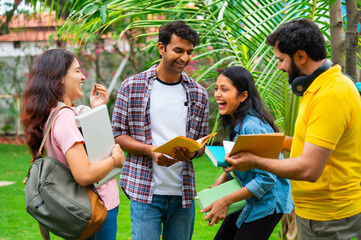 Indian university classmates standing outdoors in garden, collaborating and sharing ideas together