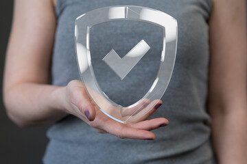 Image of a woman holding a transparent shield with a checkmark, symbolizing data protection and...