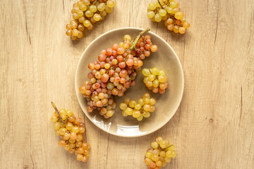 Plate full of ripe yellow grapes, top view
