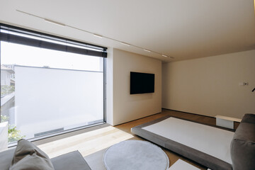 A living room with a big window and a flatscreen TV on the wall