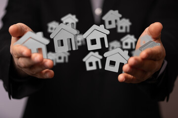 Image of a real estate agent holding many digital houses in their hands.