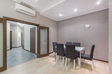 Apartments with a modern design. Dining table with chairs. A wide open door to a spacious hall.