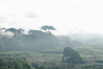 Magic mountain landscape with misty clouds floating over lush green hills and peaceful valley under...