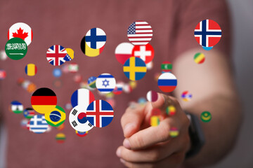 Image of a person's hand interacting with a digital display of world flags, symbolizing global...