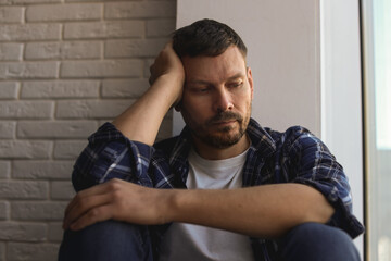 Obraz premium Depressed man sitting near window at home
