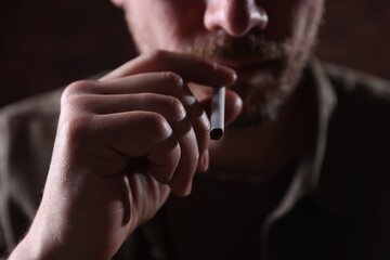 Man smoking cigarette on blurred background, closeup