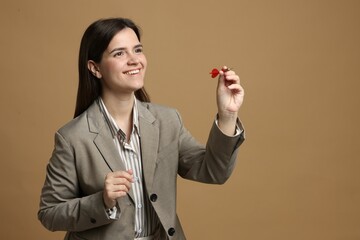 Targeting. Smiling businesswoman with dart aiming on beige background