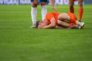 The injured footballer lies on the pitch and the opponent apologizes for the foul.