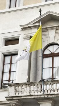 The Vatican flag flutters in the wind on a building in the Vatican