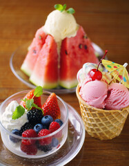 Summertime treats featuring ice-cream garnished with fresh fruits selection of watermelon, strawberries, blackberries and cherry arranged on the table. Summer delicious dessert