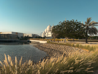 Grand mosque exterior view from lake, lush green landscape, picturesque mosque view 