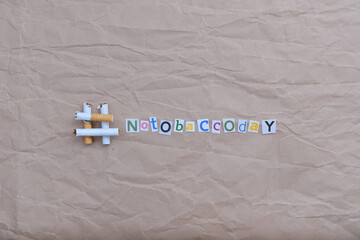 The hashtag "No Tobacco Day" made of cut-out letters and broken cigarettes on a crumpled kraft paper background. Copy space.