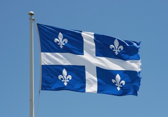 Fototapeta premium Quebec flag waving against a clear blue sky, showcasing the fleur-de-lis emblem