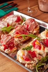 Assorted Italian bruschetta served on rustic bread with toppings like octopus, cured meats, ricotta, tomatoes, and anchovies, close-up view.