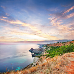 Mesmerizing sunset at cape Fiolent with bushes grass and rocks at foreground