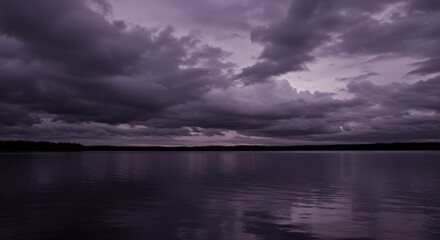 Fototapeta premium Dramatic cloudy sky over a still lake reflecting the dark sky at dusk, creating a serene and peaceful landscape with a moody and atmospheric feel