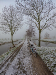 A frozen country road specific to rural Holland during a frosty winter. Walking path along the famous Dutch canals and windmills