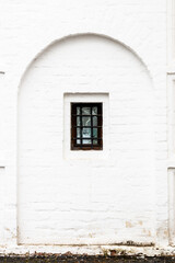 barred window in old white monastery wall