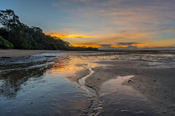 Beach sunset at low tide, looking west from Moorong Beach, toward Cleveland Point on the horizon. Coochiemudlo Island, Queensland, Australia.