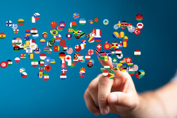 A hand interacts with a digital display of world flags, symbolizing global connection and...