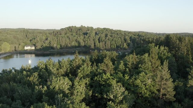 Aerial view revealing lake surrounded by vast of dense green forest, Marcillac La Croisille, France