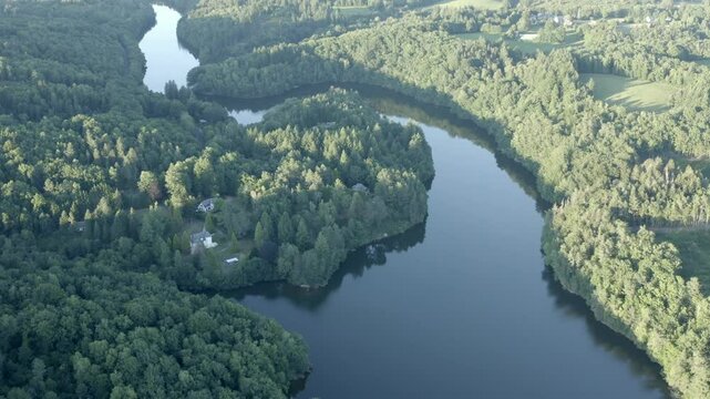 Aerial view of vast winding river or lake surrounded by dense green forest landscape, Marcillac La Croisille, France