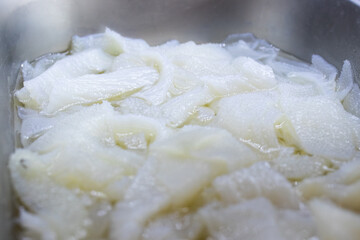 Fresh raw beef tripe soaked in water, displayed in a stainless steel tray. Commonly used in Asian cuisine, this offal ingredient is prepared for cooking or further processing.