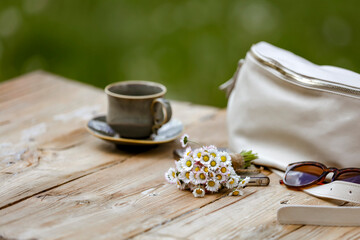 Spring or summer composition with female stuff on wooden garden table with natural outdoor green lush foliage background. Copy space for products.