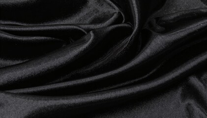 Obraz premium A luxurious piece of black silk fabric drapes elegantly, showcasing its smooth texture and subtle sheen, perfect for high-end fashion or upholstery.